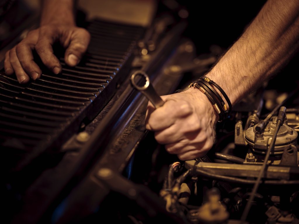 Closeup of a wrench in an engine bay in the hand of a mechanic.