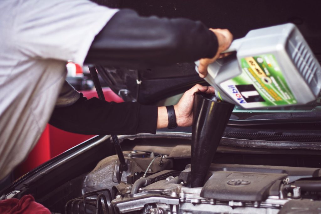 Closeup of oil pouring into the internal combustion engine of a Toyota.