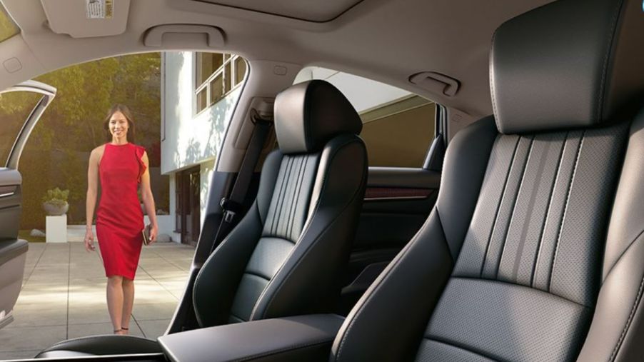 Black interior of a Honda Accord Touring with black leather seats that are heated and ventilated. The passenger-side door is open and you can see a white woman in a red dress walking toward the car