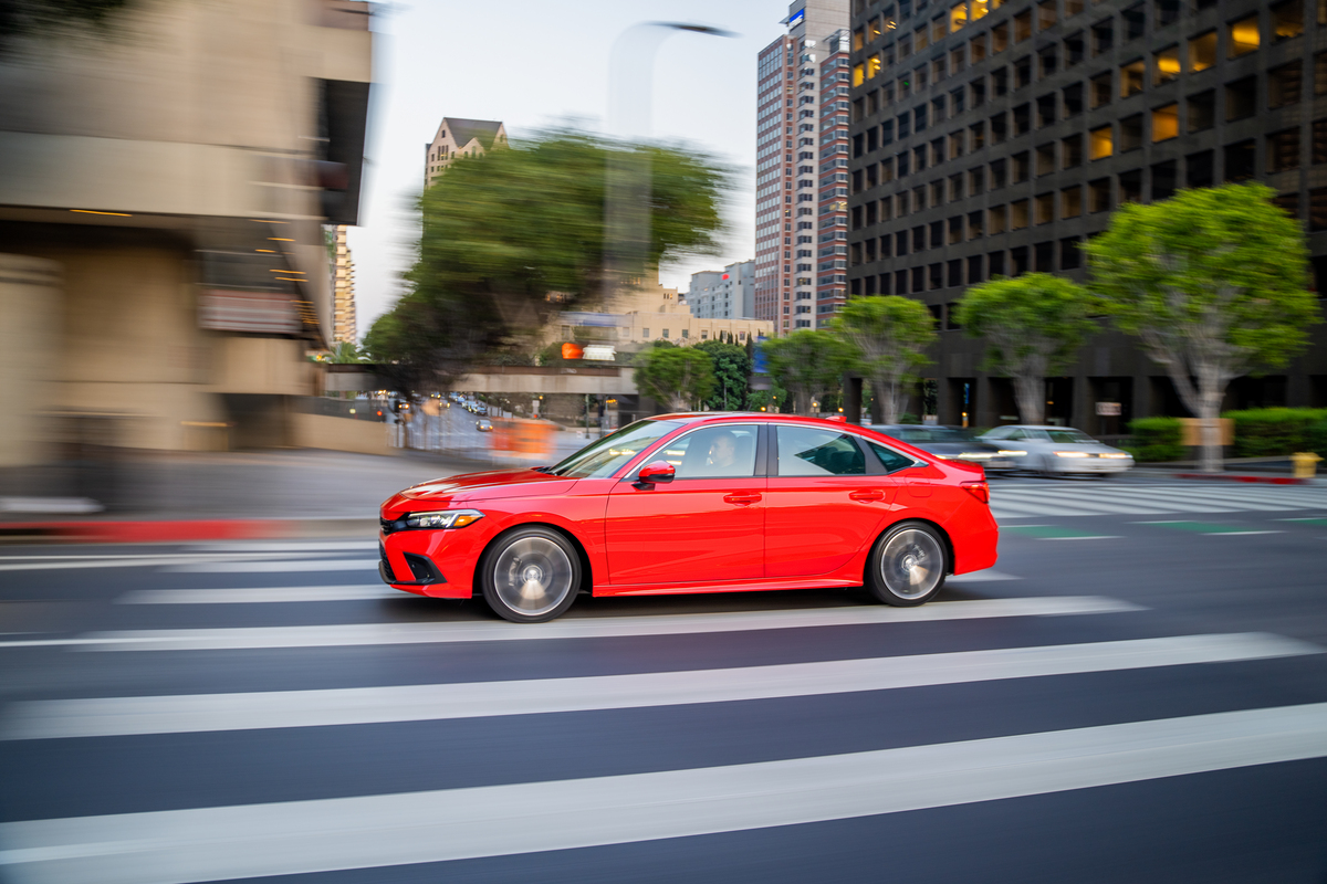 Moving shot of a red, 11th-generation 2022 Honda Civic driving in a city