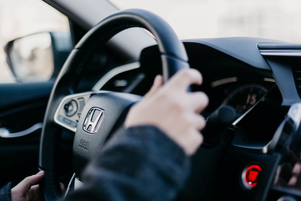 Close up of hands on a Honda steering wheel. The new HondaTrue Used certified pre-owned program can help more drivers get into older model year Honda cars