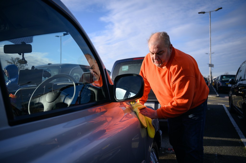 A man cleans his car. A detail is one vital things you can't forget before leaving a dealer with a used car
