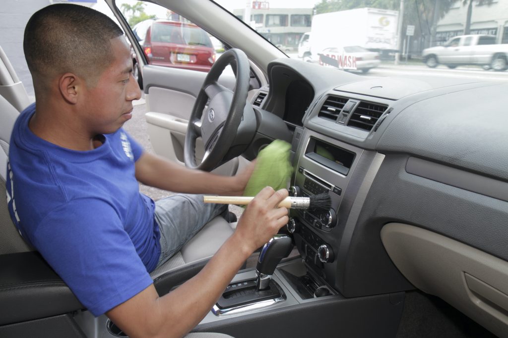 A man cleaning the dashboard of a car. 