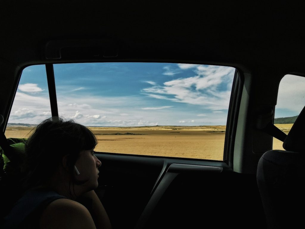 A passenger looks out a car window