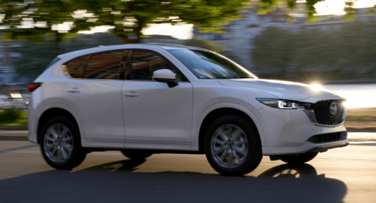 A white 2022 Mazda CX-5 small SUV is driving on the road.