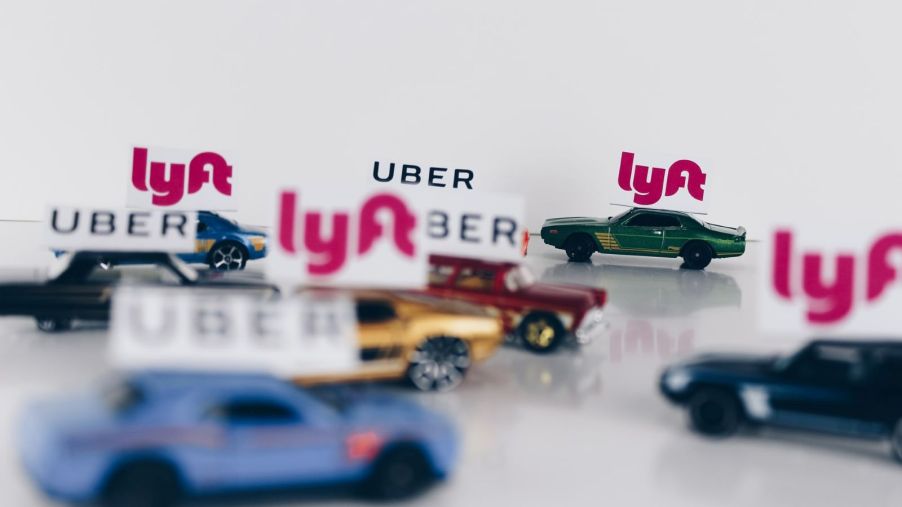 Set of toy cars collected on a flat surface. Each of the toy cars has either an Uber or Lyft sign on it
