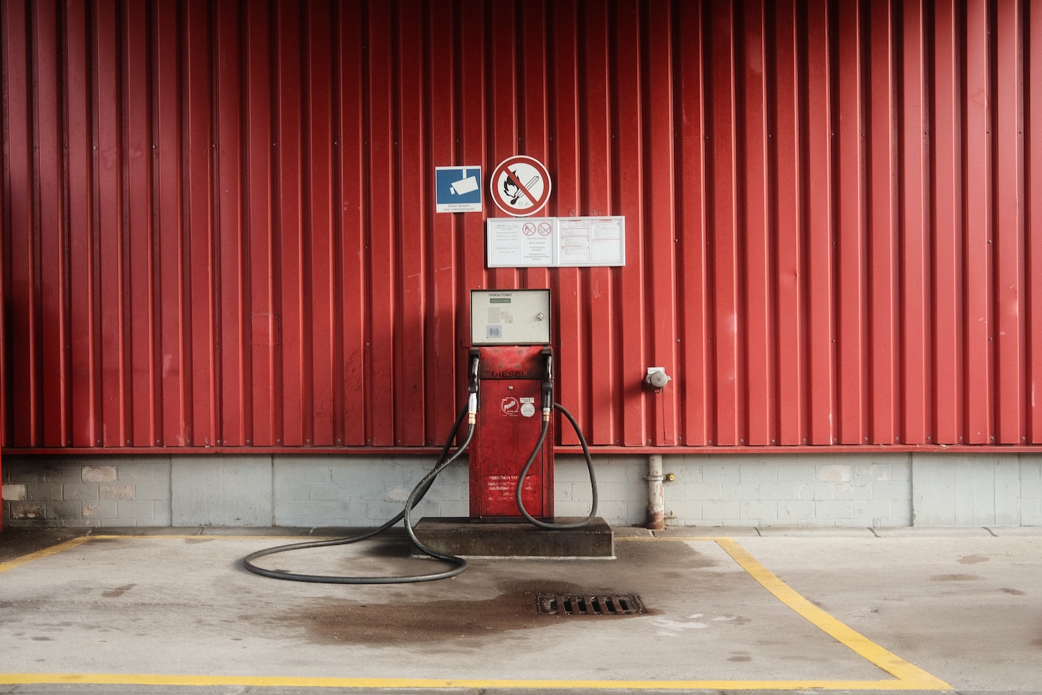 Red off road diesel fuel pump against a red metal wall.