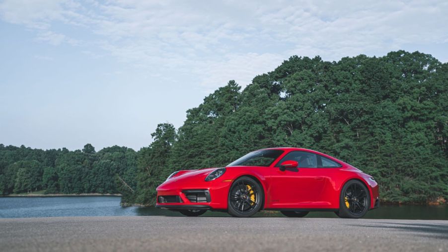 Bright red 2022 Porsche 911 GT3 sports car parked next to a lake