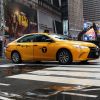 A NYC yellow cab driving in the city. Recently, Uber agreed to list taxis on its app