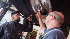 Vehicle maintenance technicians inspect a car