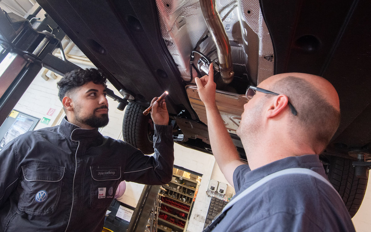 Vehicle maintenance technicians inspect a car