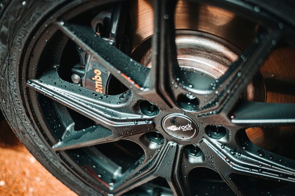 Close-up of a Brock wheel covered in water droplets, with Brembo brakes showing through the spokes
