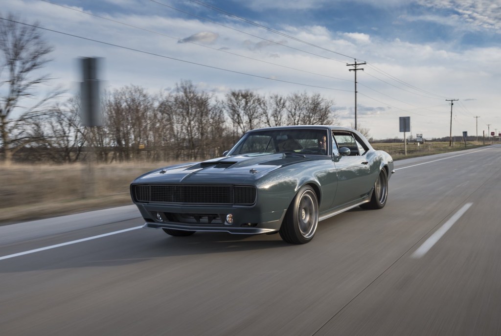 Green 1967 Chevy Camaro driving down a rural highway.