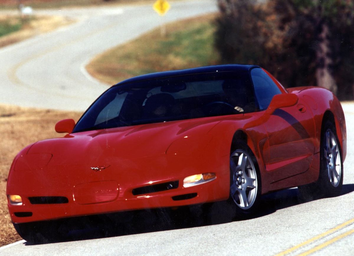 Red 1997 Chevrolet Corvette driving along a winding road
