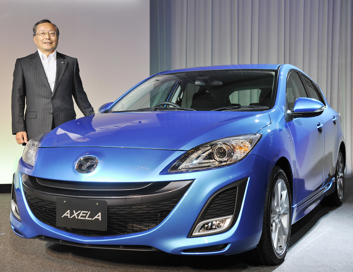 Mazda president with blue 2010 Mazda3 at 2009 Tokyo Auto Show