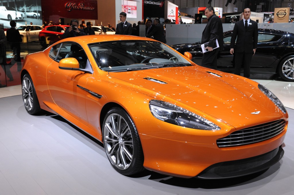 An orange 2011 Aston Martin Virage on stage at the 2011 Geneva Motor Show