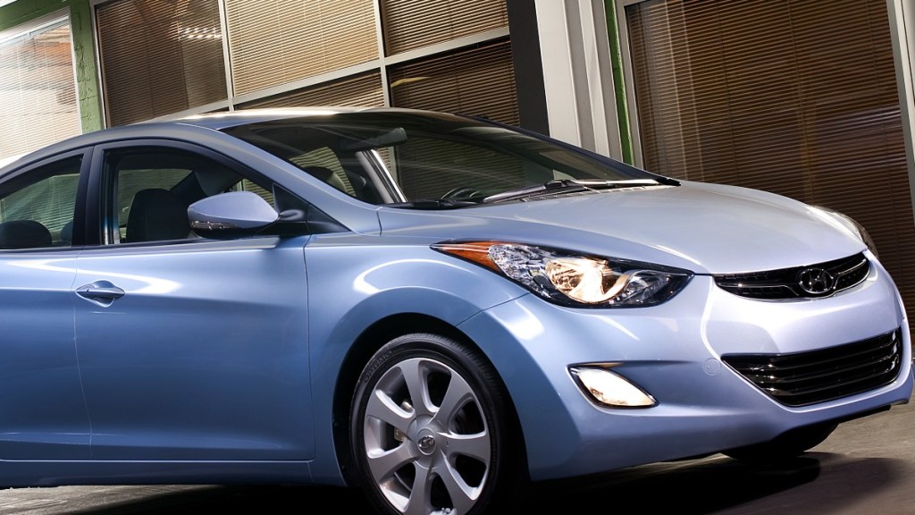 a light blue 2013 hyundai elantra parked with its headlights and fog lights on
