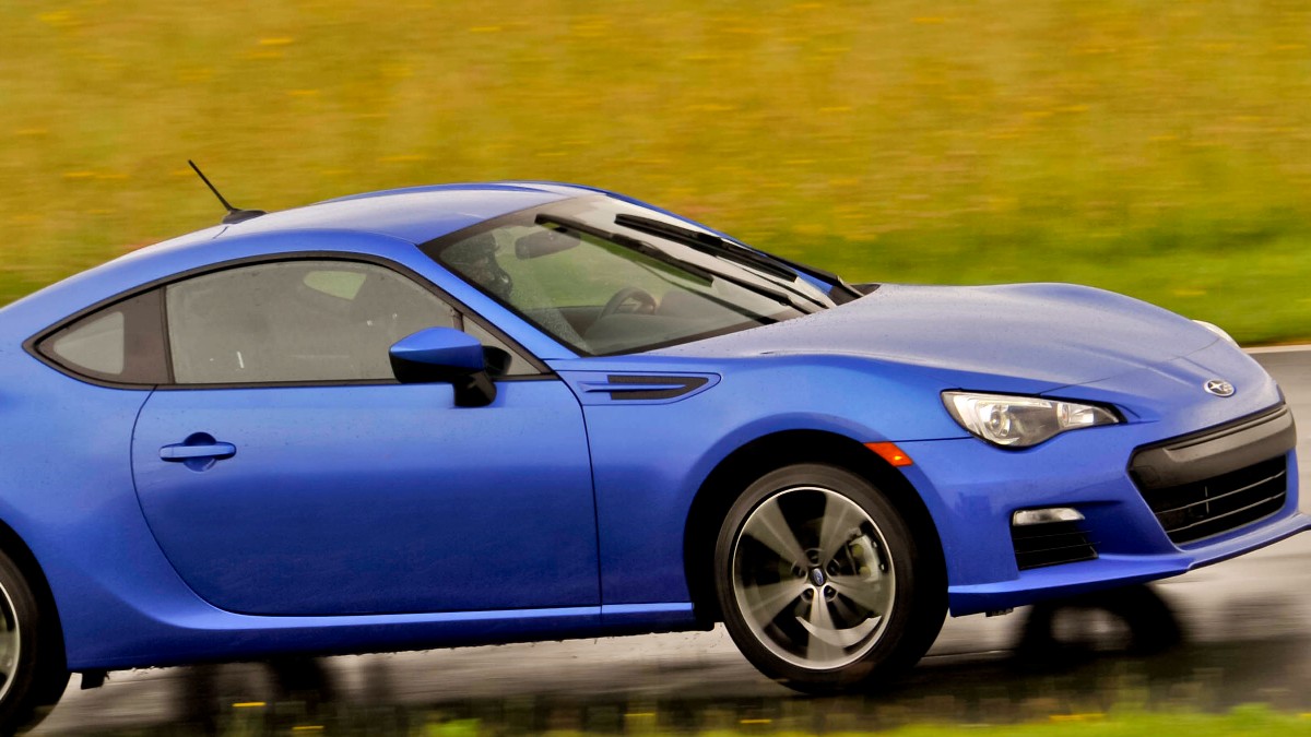 A blue 2013 Subaru BRZ is being tested on a track during the rain