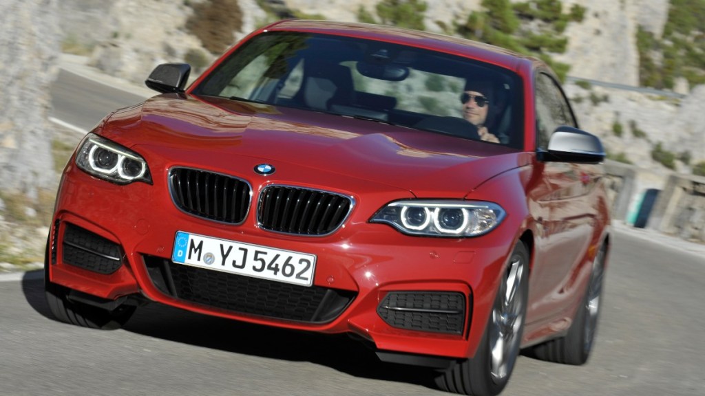 a red 2014 BMW BMW 2 series drives around a winding mountain road, showing off its agile handling