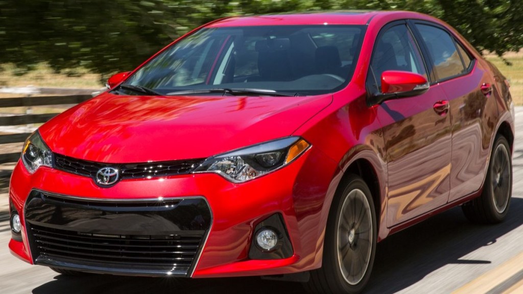 A red 2014 Toyota Corolla drives along showing off its modern style