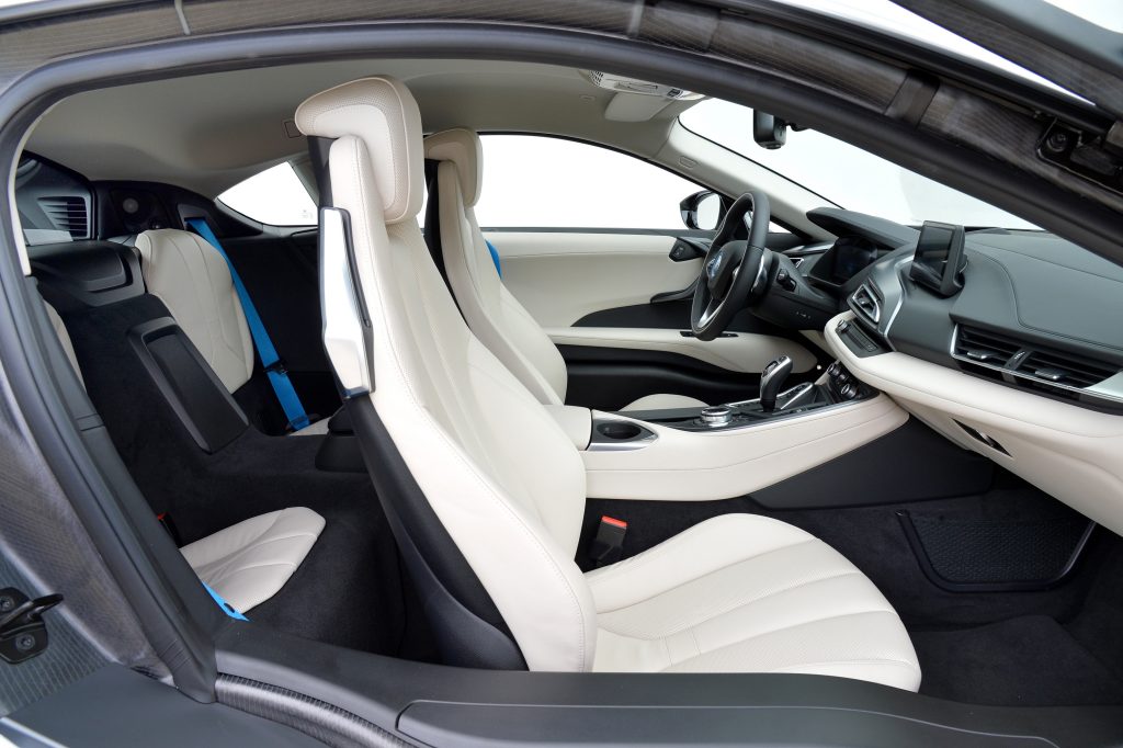 The white leather seats and black dashboard of a 2015 BMW i8 in a white studio