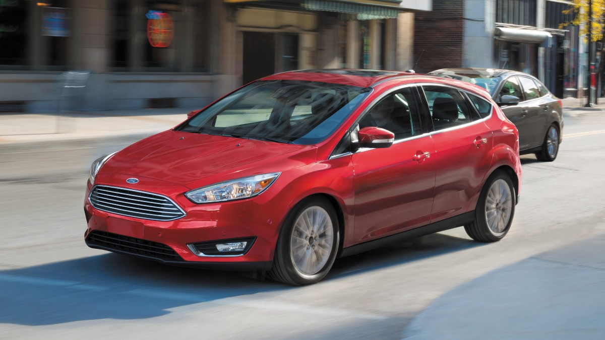 a red 2016 Ford Focus Titanium driving around a city street during the day