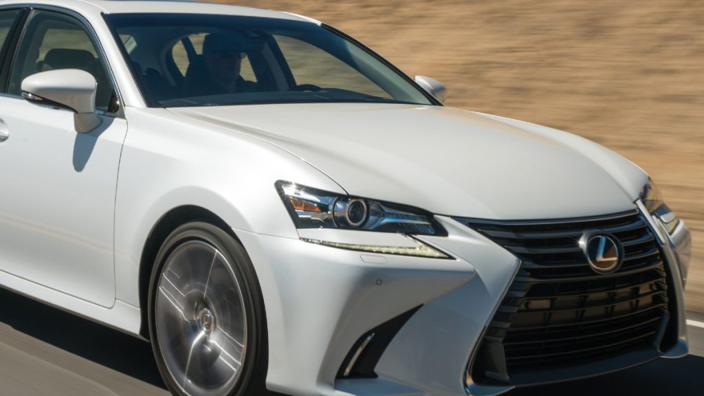 A white 2017 Lexus GS zooms along the road. A good example of a certified pre-owned luxury sedan