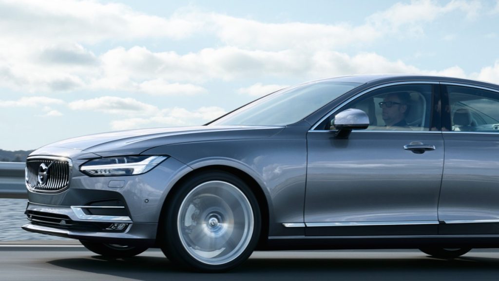 A grey 2017 Volvo S90 is driven along the ocean