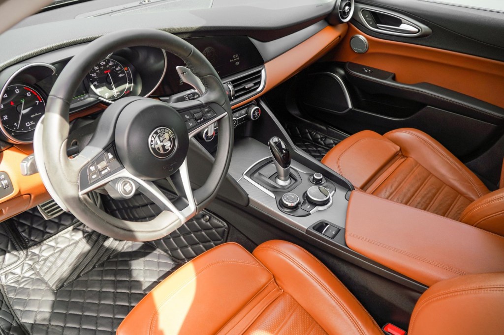 The tan-leather front sport seats and black dashboard of a 2018 Alfa Romeo Giulia Q2 Ti Sport