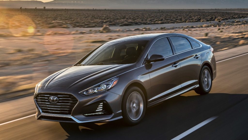 a grey 2018 hyundai sonata drives in the desert with the sun reflecting off its sleek body