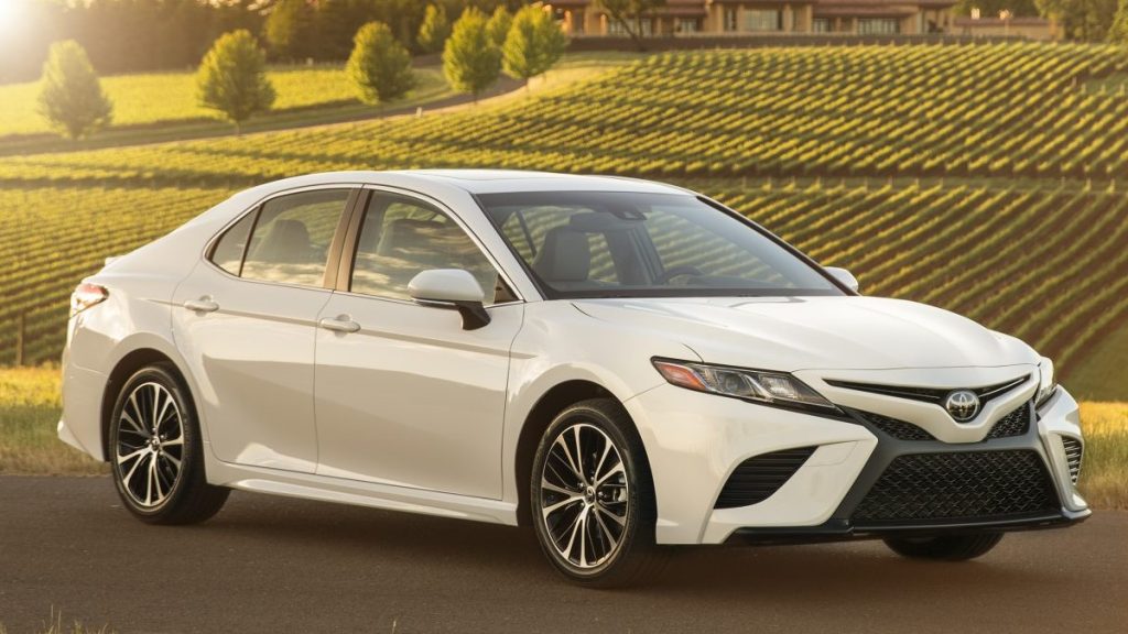 A white 2019 Toyota Camry SE parked with a wheat field behind it during sunset
