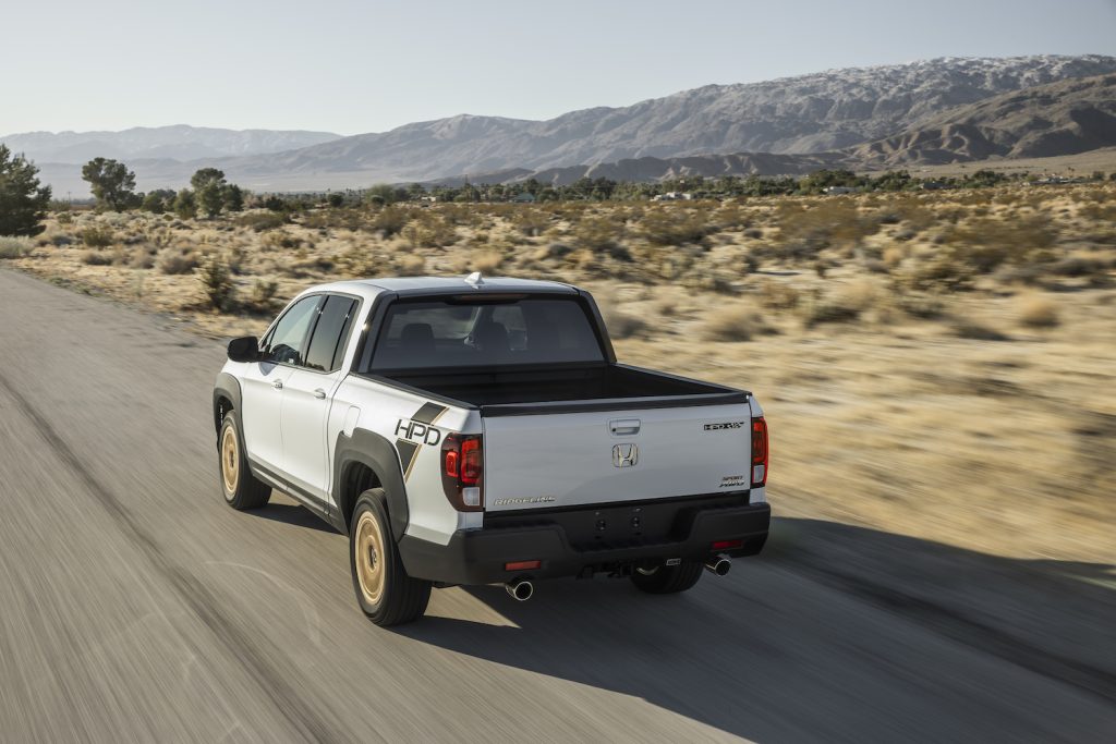 White Honda Ridgeline driving down a road in the desert - its premium audio system could use some updating.