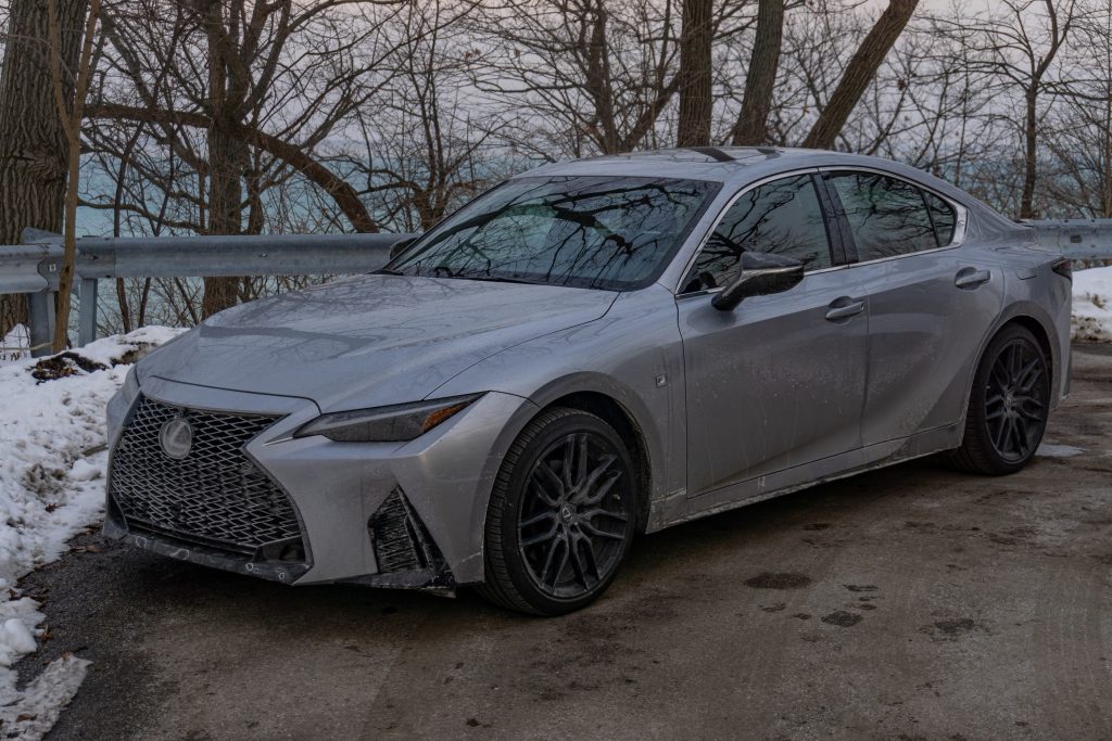 A silver 2021 Lexus IS 350 AWD F Sport with Dynamic Handling Package parked by a snowy forest