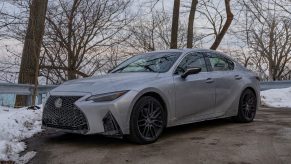 A silver 2021 Lexus IS 350 F Sport AWD with Dynamic Handling Package next to a snowy forest