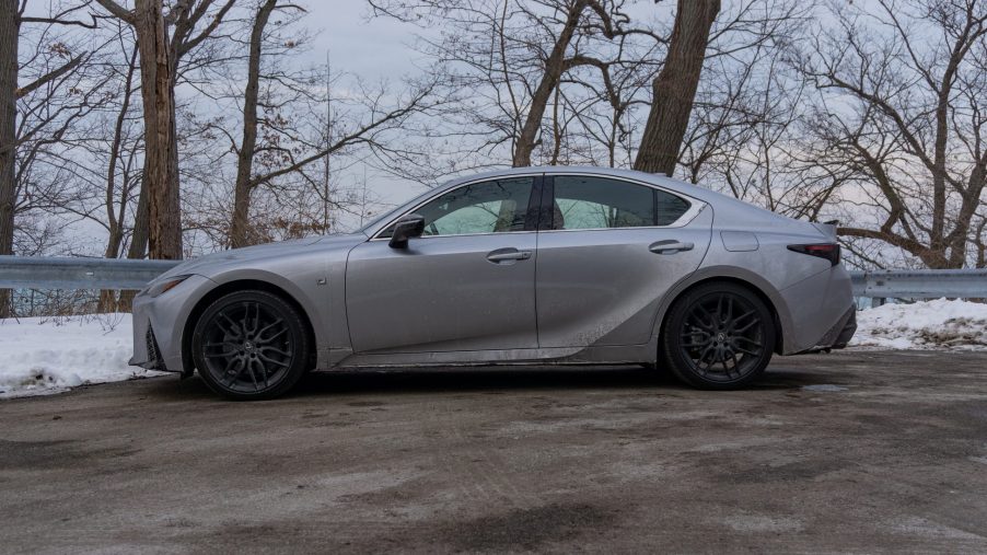 A side view of a silver 2021 Lexus IS 350 AWD F Sport with Dynamic Handling Package next to a snowy forest