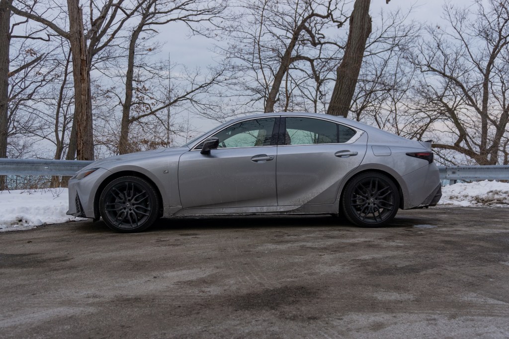 A side view of a silver 2021 Lexus IS 350 AWD F Sport with Dynamic Handling Package next to a snowy forest