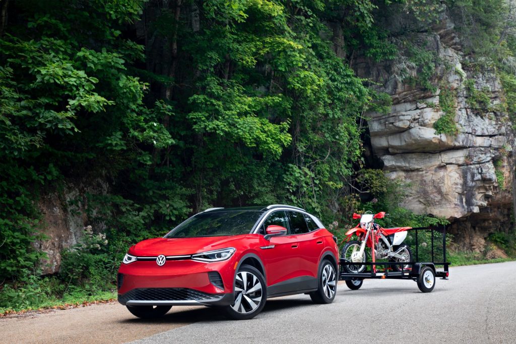 2021 Volkswagen ID.4 AWD Pro S with Gradient Package towing a red motorbike and parked by a grassy cliffside