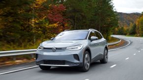 2021 Volkswagen ID.4 AWD all-electric compact SUV in gray driving on a forest highway