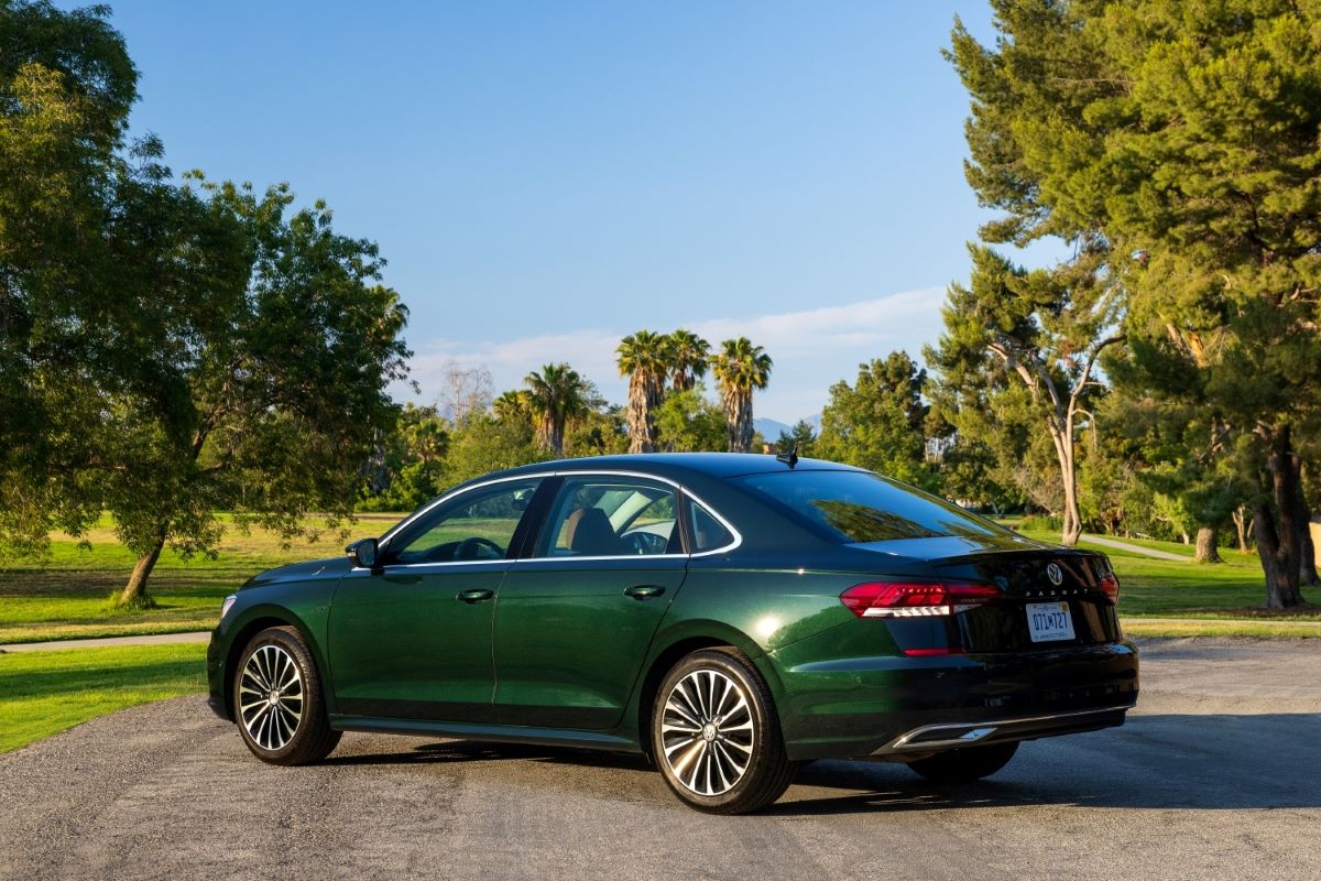 Rear side-angle view of a dark green 2021 VW Passat sedan with some of the best trunk space in its class