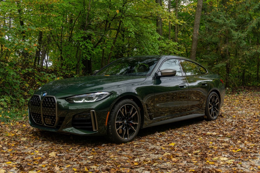 A green 2022 BMW 4 Series M440i xDrive Gran Coupe in a leafy forest
