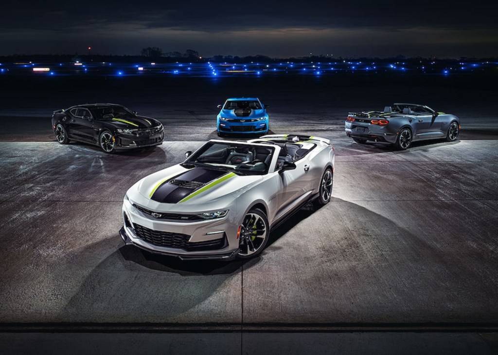 A black and blue 2022 Chevrolet Camaro Steel and Shock Special Edition Coupe and a gray Convertible behind a silver Convertible on an airstrip at night