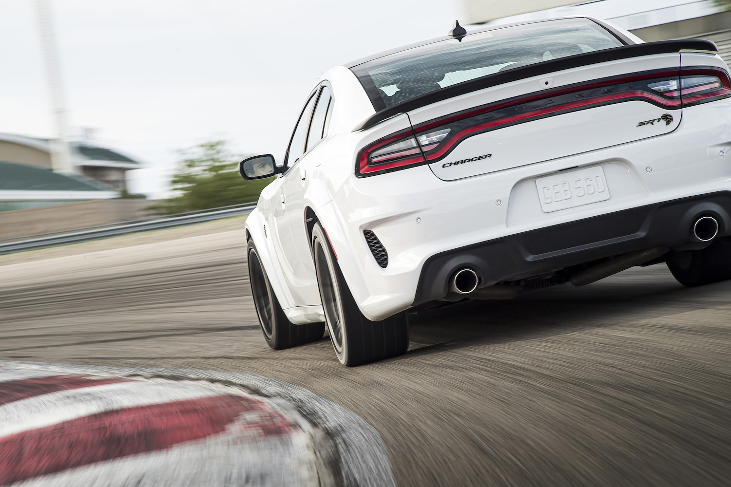 A white Dodge Charger Hellcat cornering on a racetrack.