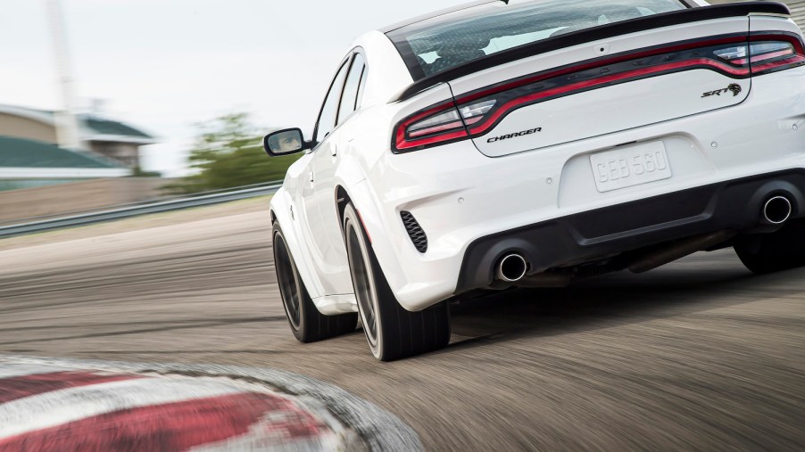 A white Dodge Charger Hellcat cornering on a racetrack.