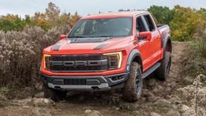 Orange 2022 Ford F-150 Raptor going through the mud. This is one of the best off-road trucks in the industry.