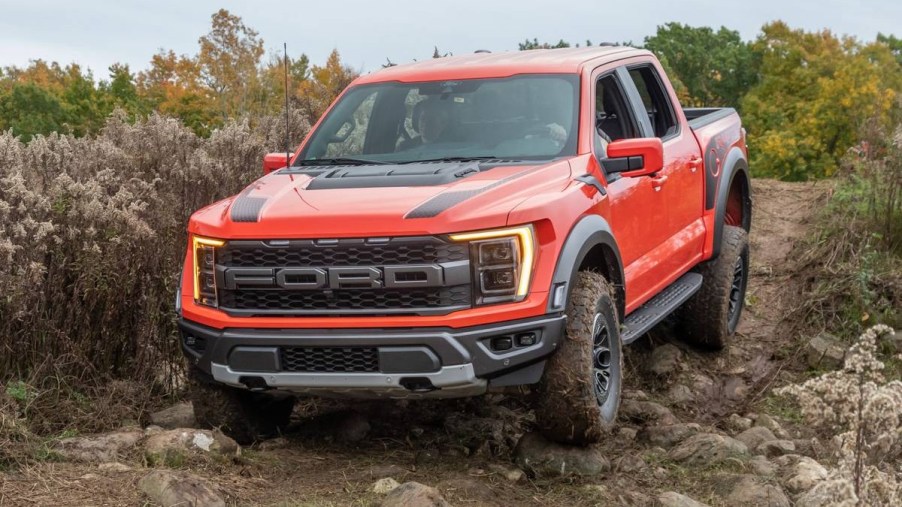 Orange 2022 Ford F-150 Raptor going through the mud. This is one of the best off-road trucks in the industry.