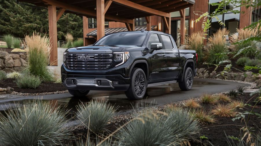 The 2022 GMC Sierra 1500 Denali Ultimate full-size premium pickup truck parked on the driveway plaza of a luxury forest home