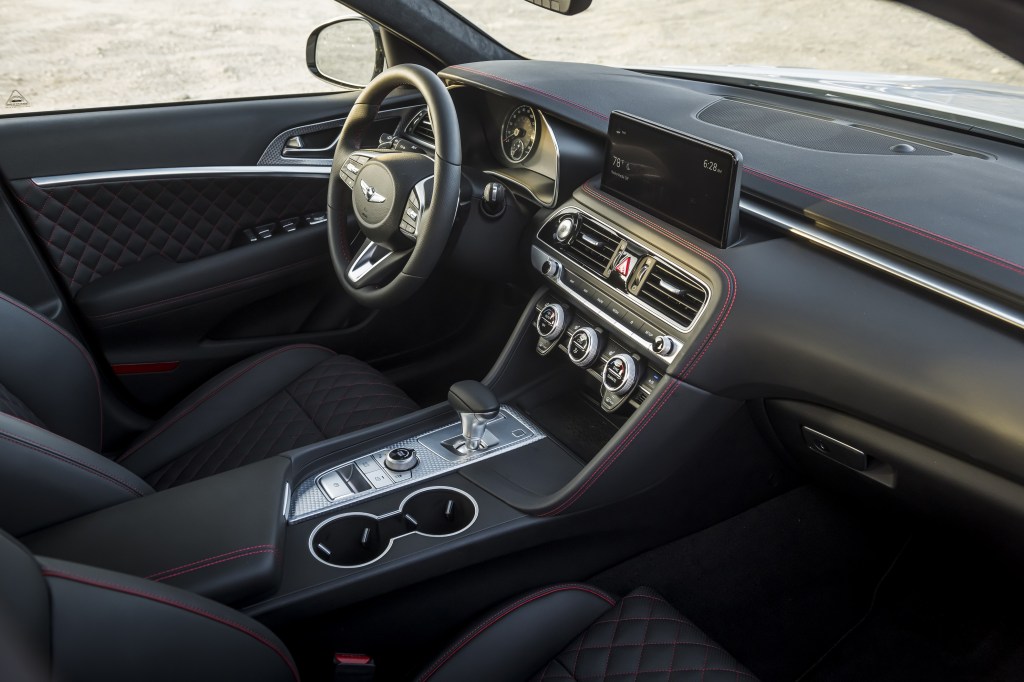 The black-and-red-stitched quilted-leather front seats and dashboard of a 2022 Genesis G70