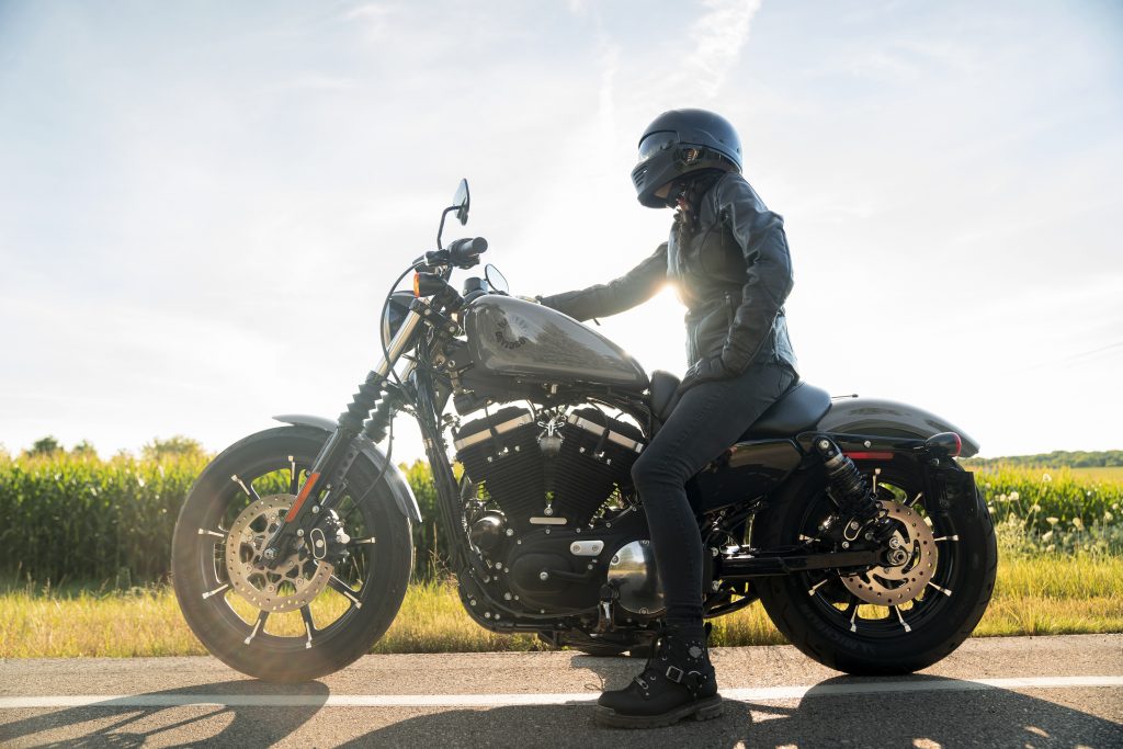 The side view of a black-clad rider on a gray 2022 Harley-Davidson Iron 883