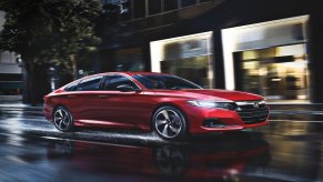 A 2022 red Honda Accord drives down a wet and rain covered city street