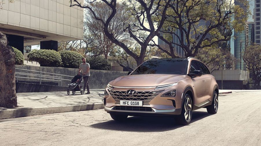 A gold color 2022 Hyundai Nexo sitting outside a building in a city environment.